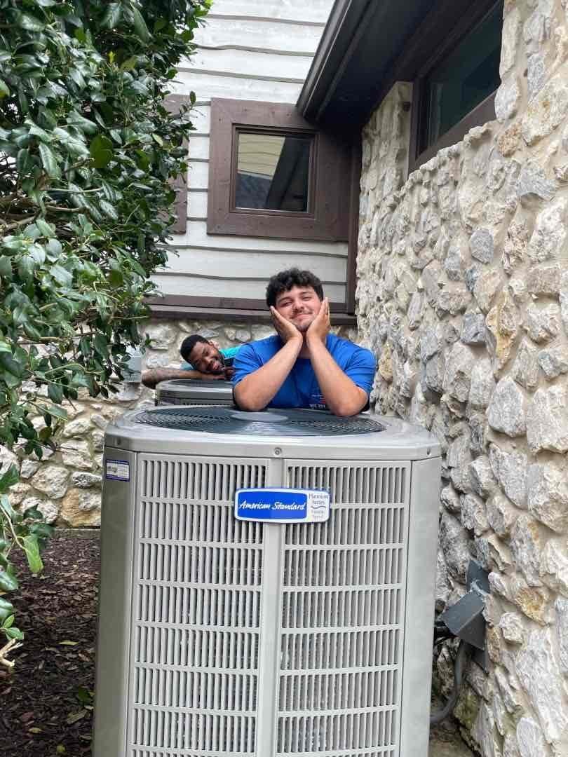 Two technicians posing behind a newly installed American Standard condenser