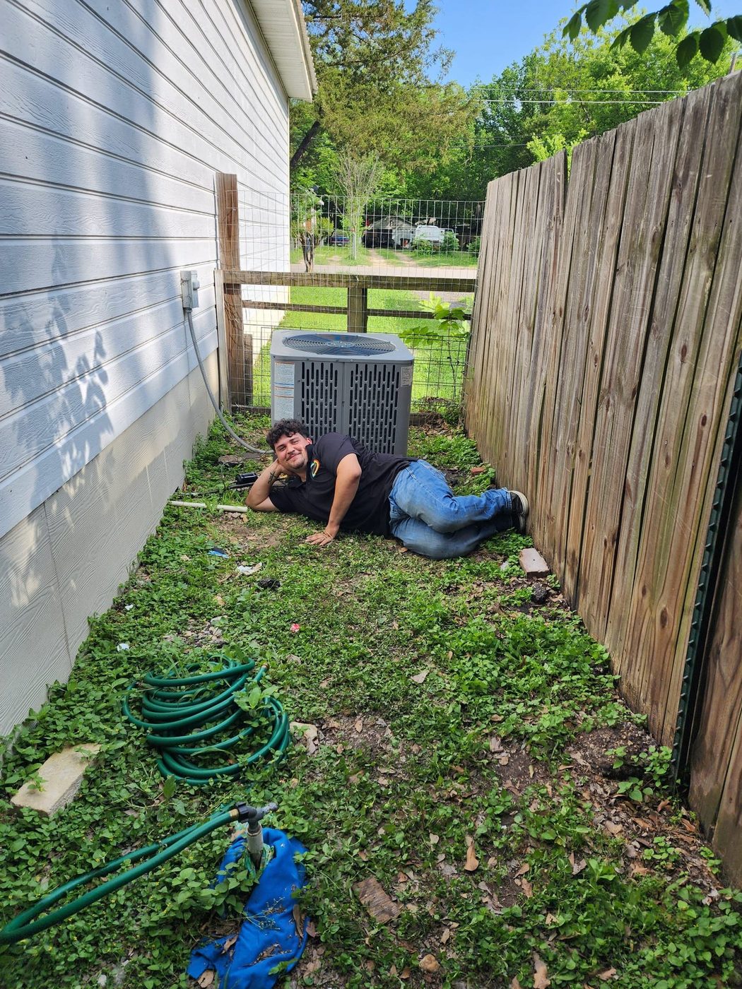 A technician relaxing on the grass beside a running condenser after a repair